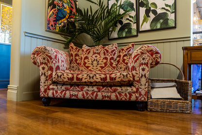 Tetrad Elgar Snuggler Sofa in Enigma Claret Fabric with deep filled seat cushions and matching scatter back cushions, curved armrests and dark wood feet