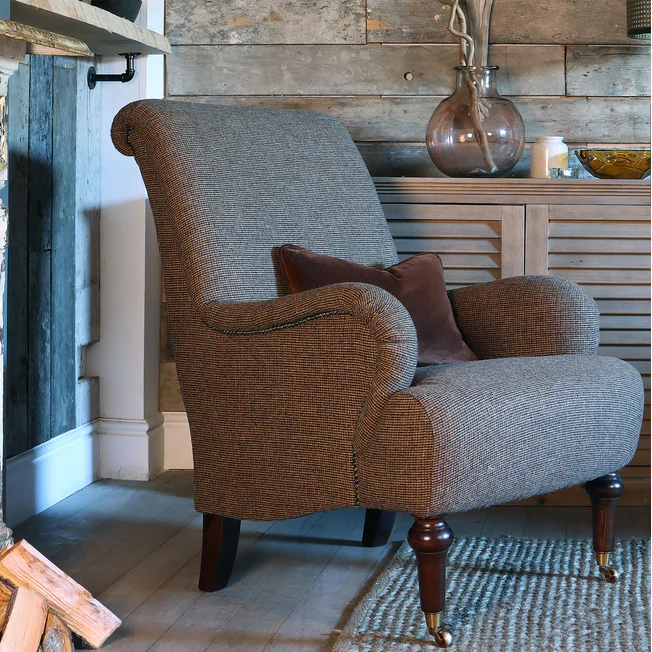 Tetrad Kenmure Chair in Basalt Herringbone patterned upholstery, featuring a classic wingback style with scrolled headrest and arms, stud detailing and dark wooden legs with front castors