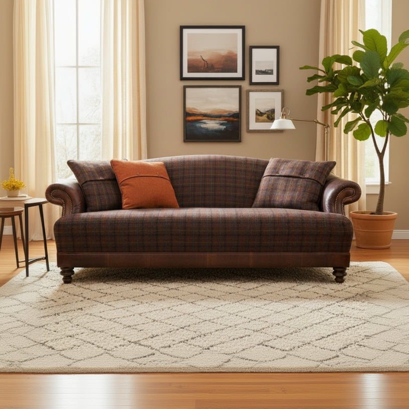 The Tetrad Taransay Midi Sofa is upholstered in Mixed Tartan Fabric and Leather accents, with brass stud detailing to the arms and complementary scatter cushions 