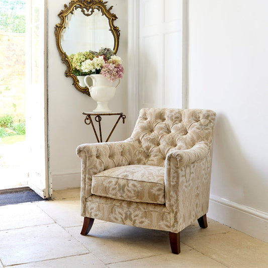 Tetrad Tate Chair in Enigma Natural fabric in a living room, showing its patterned upholstery, rolled arms and dark wooden feet.