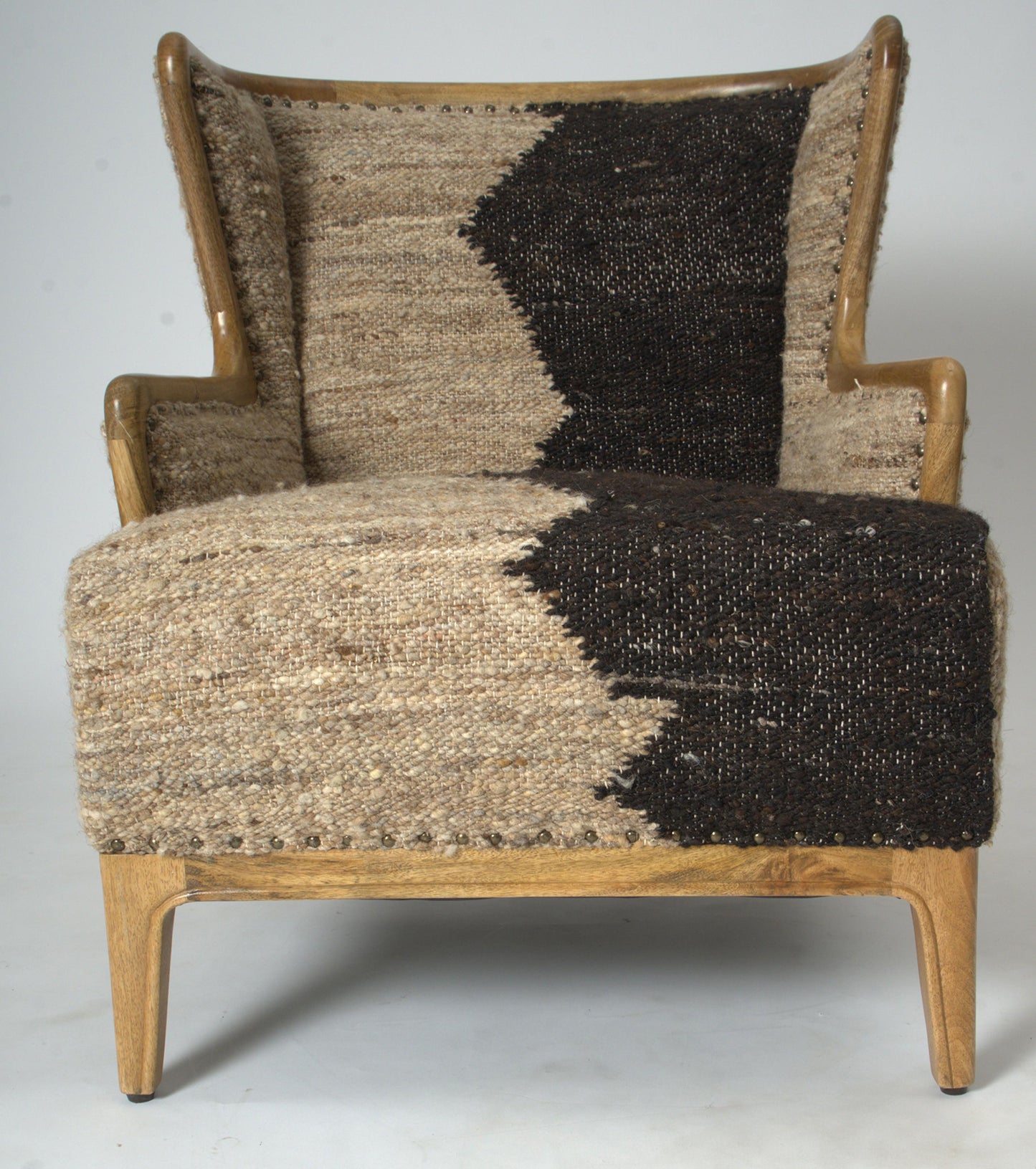 Vintage Sofa Company Ballari Chair features a wingback inspired shape with an exposed wooden frame and is upholstered in a cream and charcoal boucle style fabric, with brass stud details