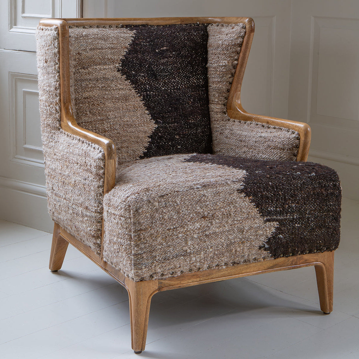 Vintage Sofa Company Ballari Chair features a mix of sculptural woodwork and textured upholstery, with a wingback inspired design and boucle style fabric in charcoal and cream colours