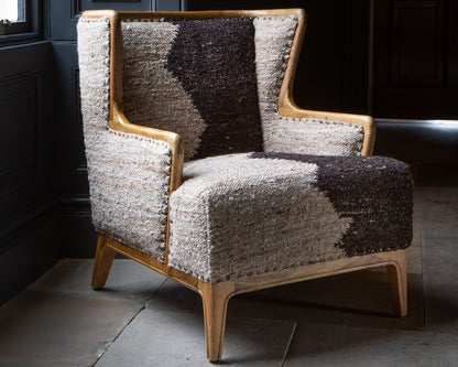 Vintage Sofa Company Ballari Chair is crafted from an exposed wooden frame, with wingback inspired design and is upholstered in cream and charcoal boucle style fabric