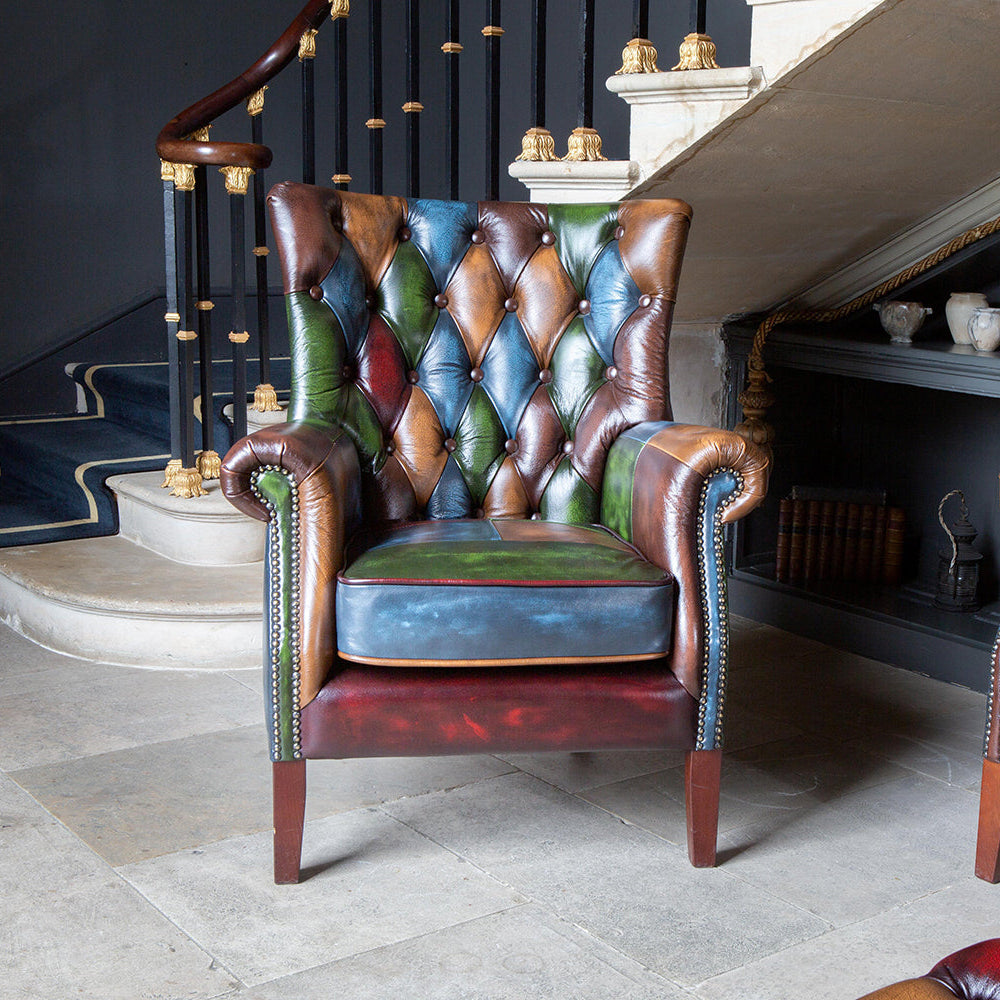 Vintage Sofa Company Bowes Rub-Off Leather Patchwork Chair features a high back rest with diamond buttoning, scrolled arms, brass stud detailing and dark wooden legs