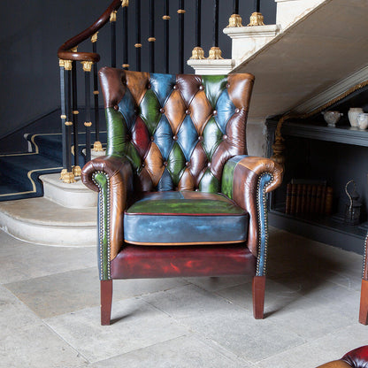 Vintage Sofa Company Bowes Rub-Off Leather Patchwork Chair features a high back rest with diamond buttoning, scrolled arms, brass stud detailing and dark wooden legs