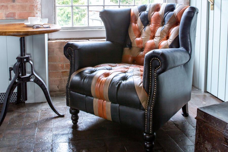 Vintage Sofa Company Crompton Union Jack Armchair in Leather features a tall high winged back design with scrolled armrests, brass stud detailing and black turned wooden legs 