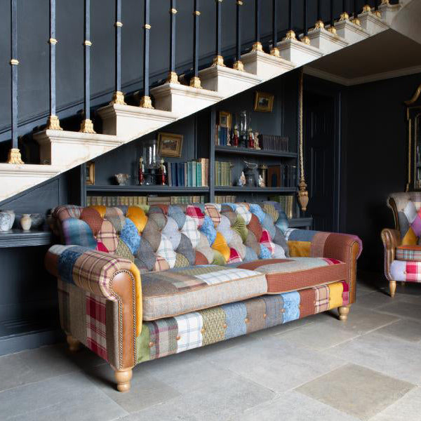 Vintage Sofa Company Dickinson 2 Seat Medium Sofa. Its patchwork upholstery, tan leather arms, brass stud detailing and mid oak legs give it a distinctive look, while the buttoned Chesterfield influence keeps the overall feel structured and substantial.