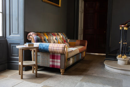 Vintage Sofa Company Dickinson Large 2.5 Seater Sofa Upholstered in Patchwork fabric with tan leather trim and brass stud detailing, and turned wooden legs.