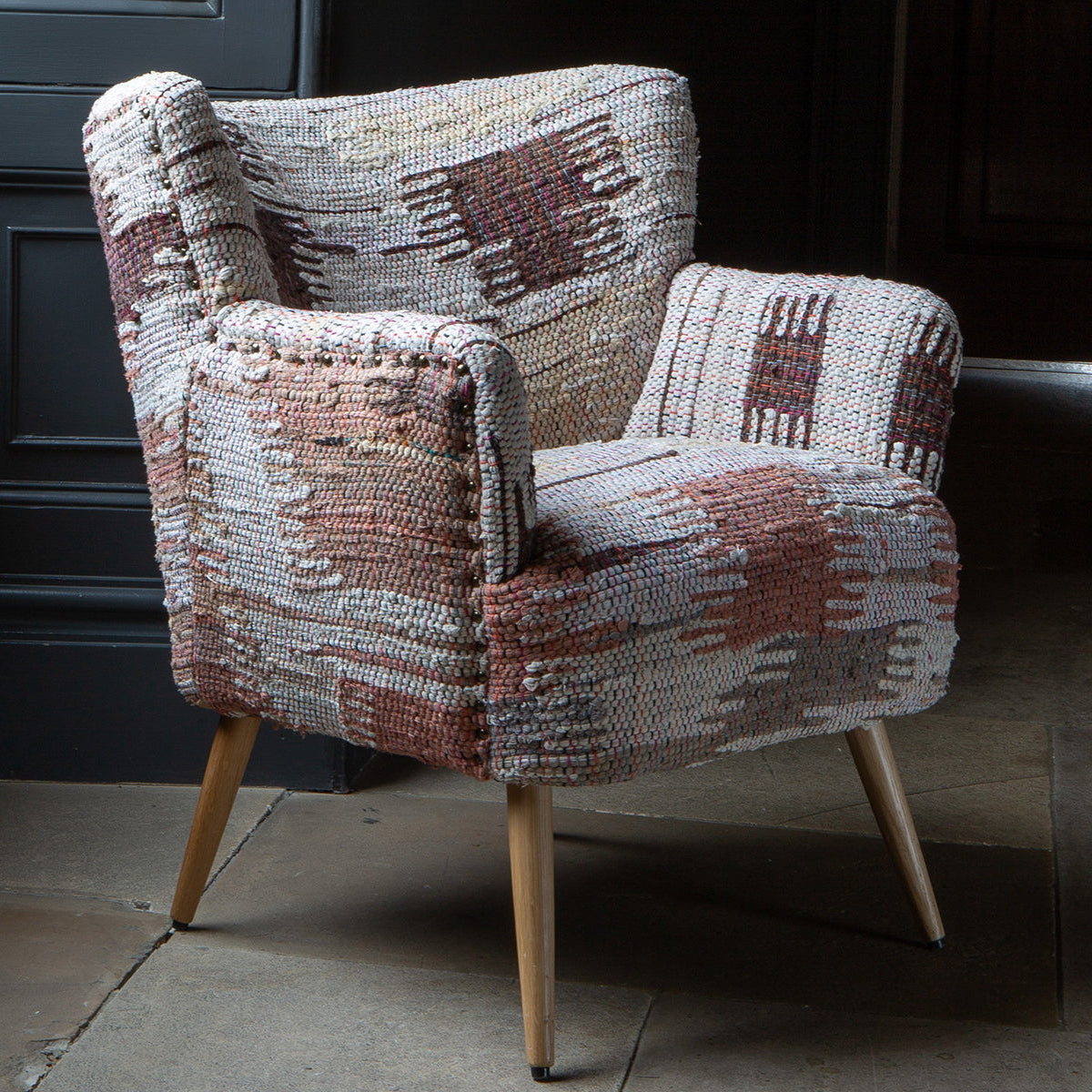 Vintage Sofa Company Hansi Chair features a textured woven fabric with soft muted tones in an abstract pattern, with brass stud detailing and tapered light wooden legs