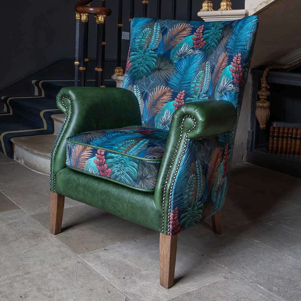 Vintage Sofa Company Hexham Chair is upholstered in Kingfisher Fabric and Bottle Green Leather, and features scrolled arms with brass stud detailing, and dark wooden legs