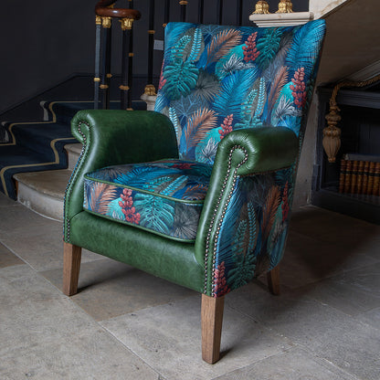 Vintage Sofa Company Hexham Chair is upholstered in Kingfisher Fabric and Bottle Green Leather, and features scrolled arms with brass stud detailing, and dark wooden legs