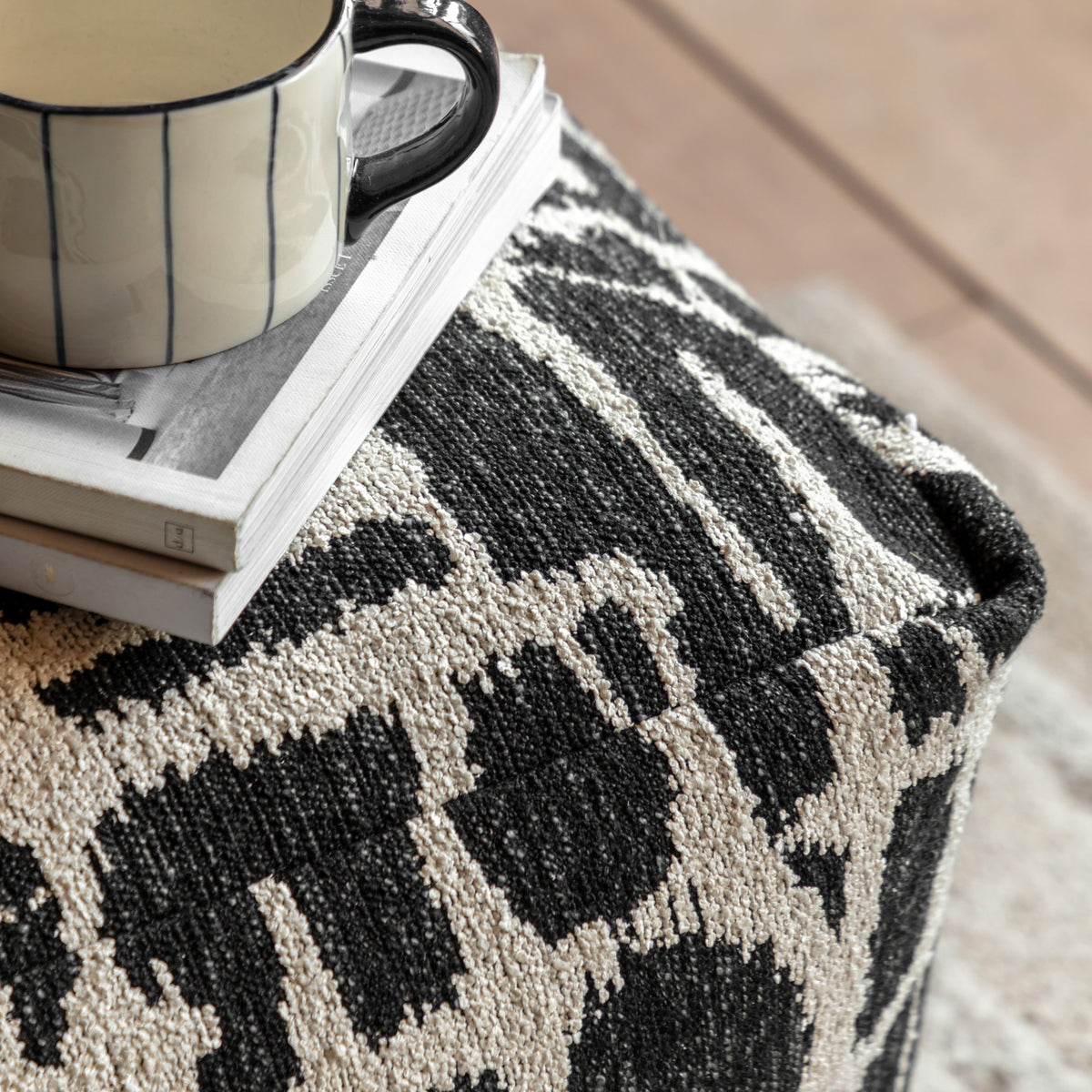 Gallery Direct Elara Jacquard Pouffe Slate 550x550x350mm - jacquard upholstery close-up with a mug and books